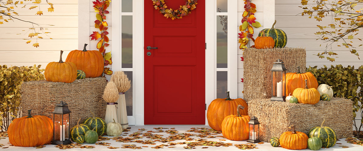 Red door on front porch with pumpkins